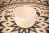White crystal singing bowl with gold geometric design on mandala mat for sound healing