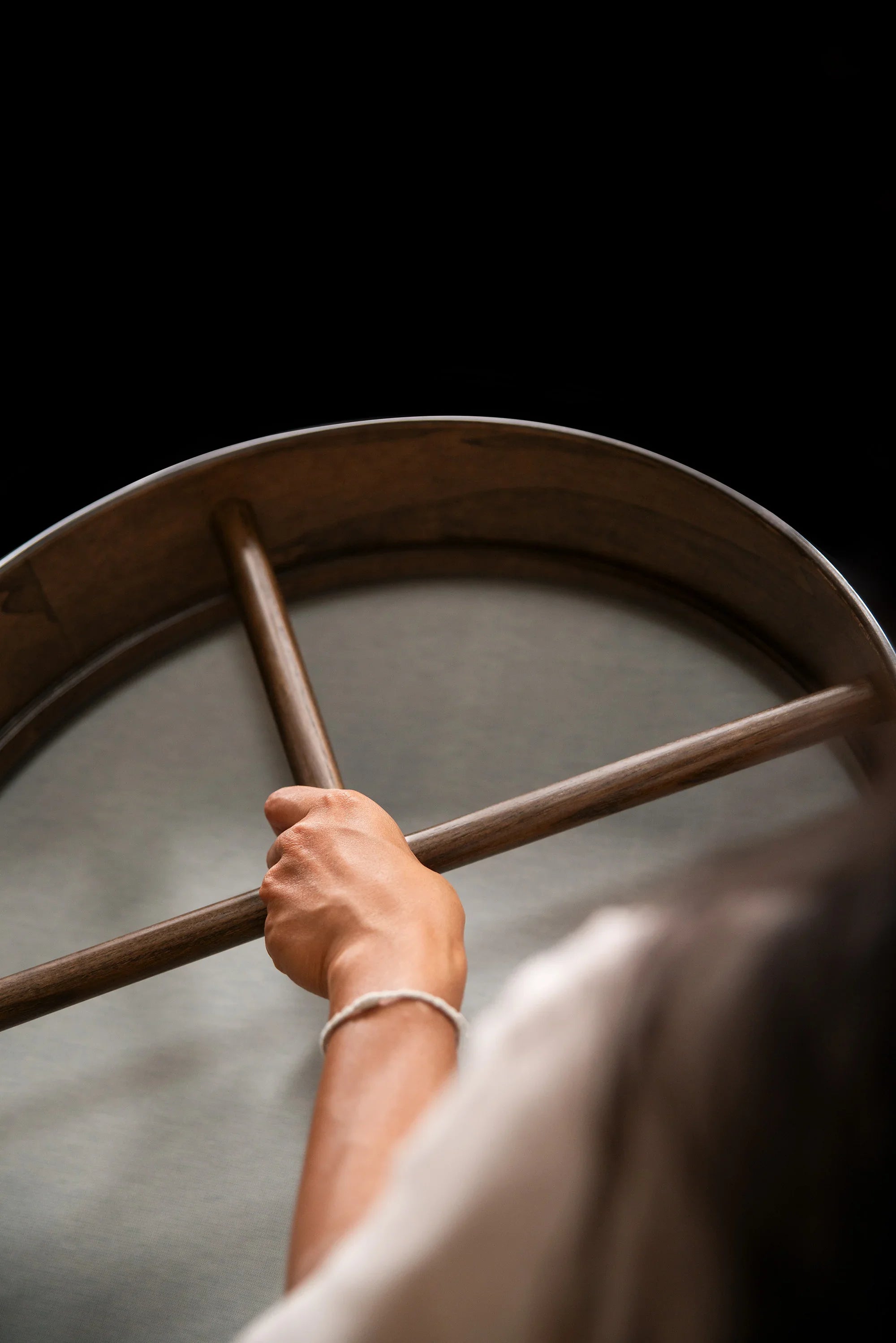 Hand holding wooden frame drum for sound healing on black background