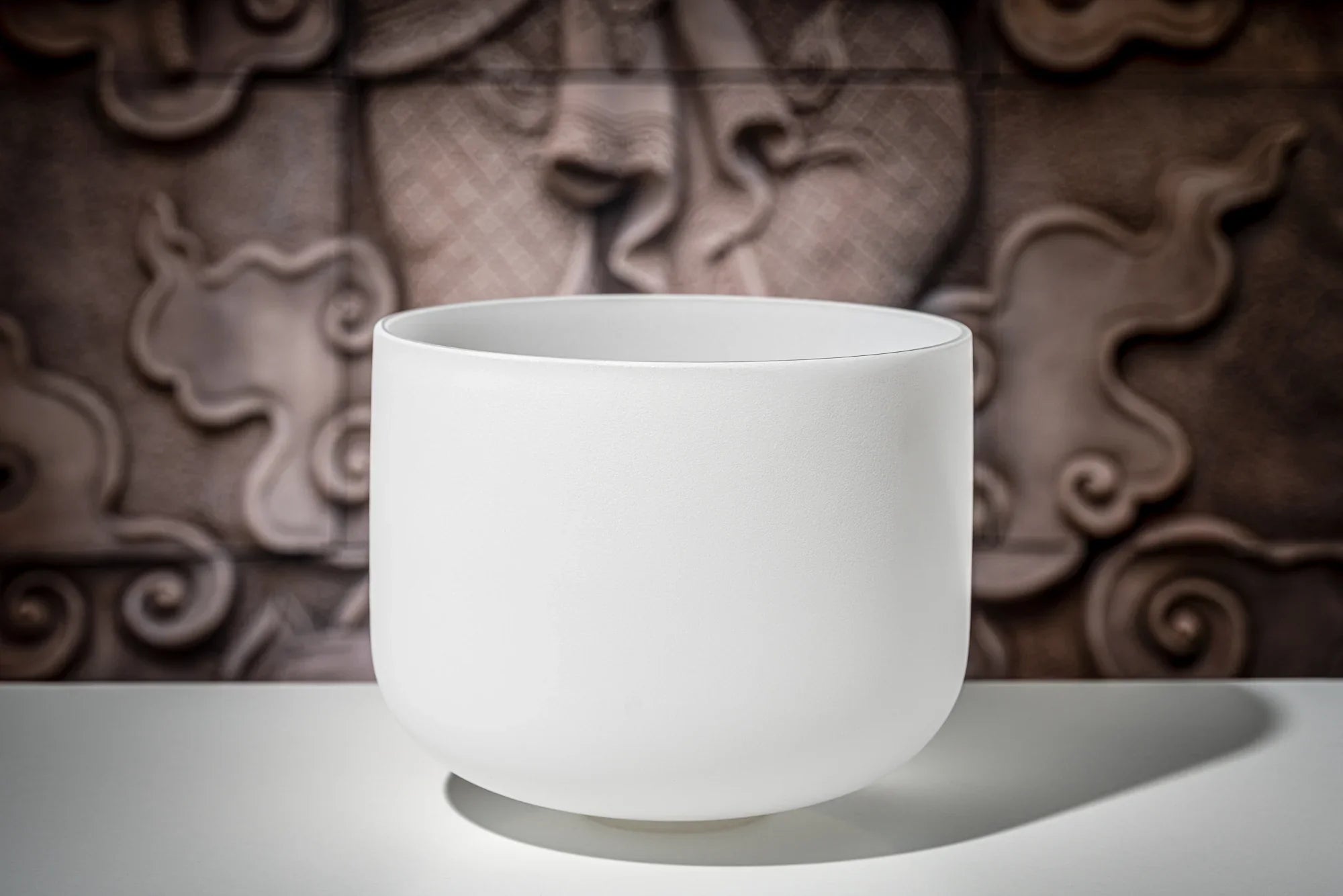 White crystal singing bowl for sound healing on a table with a textured background