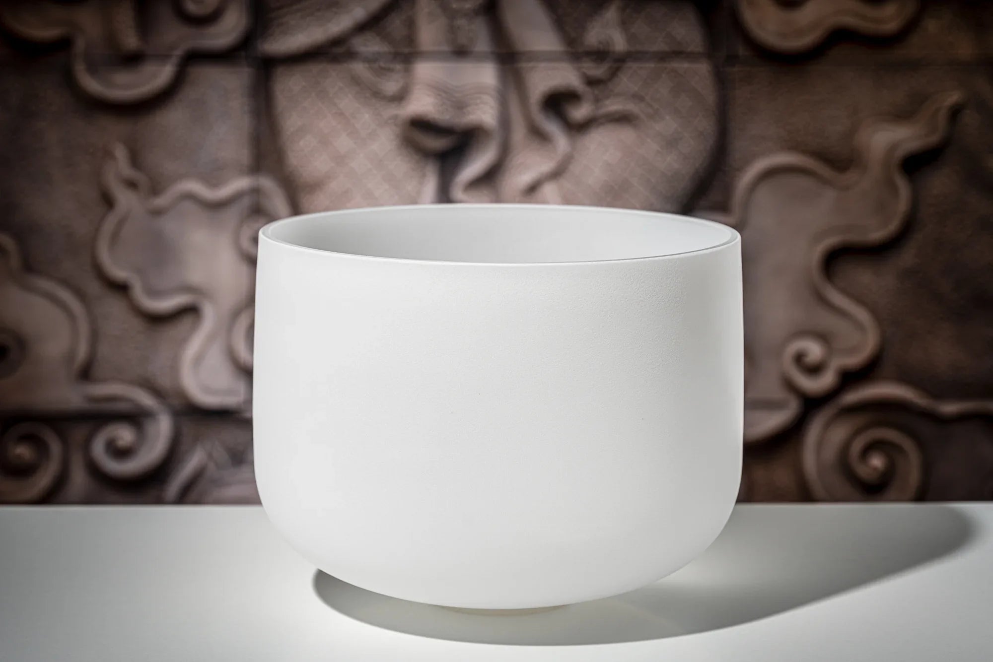 White crystal singing bowl for sound healing on a table with artistic background