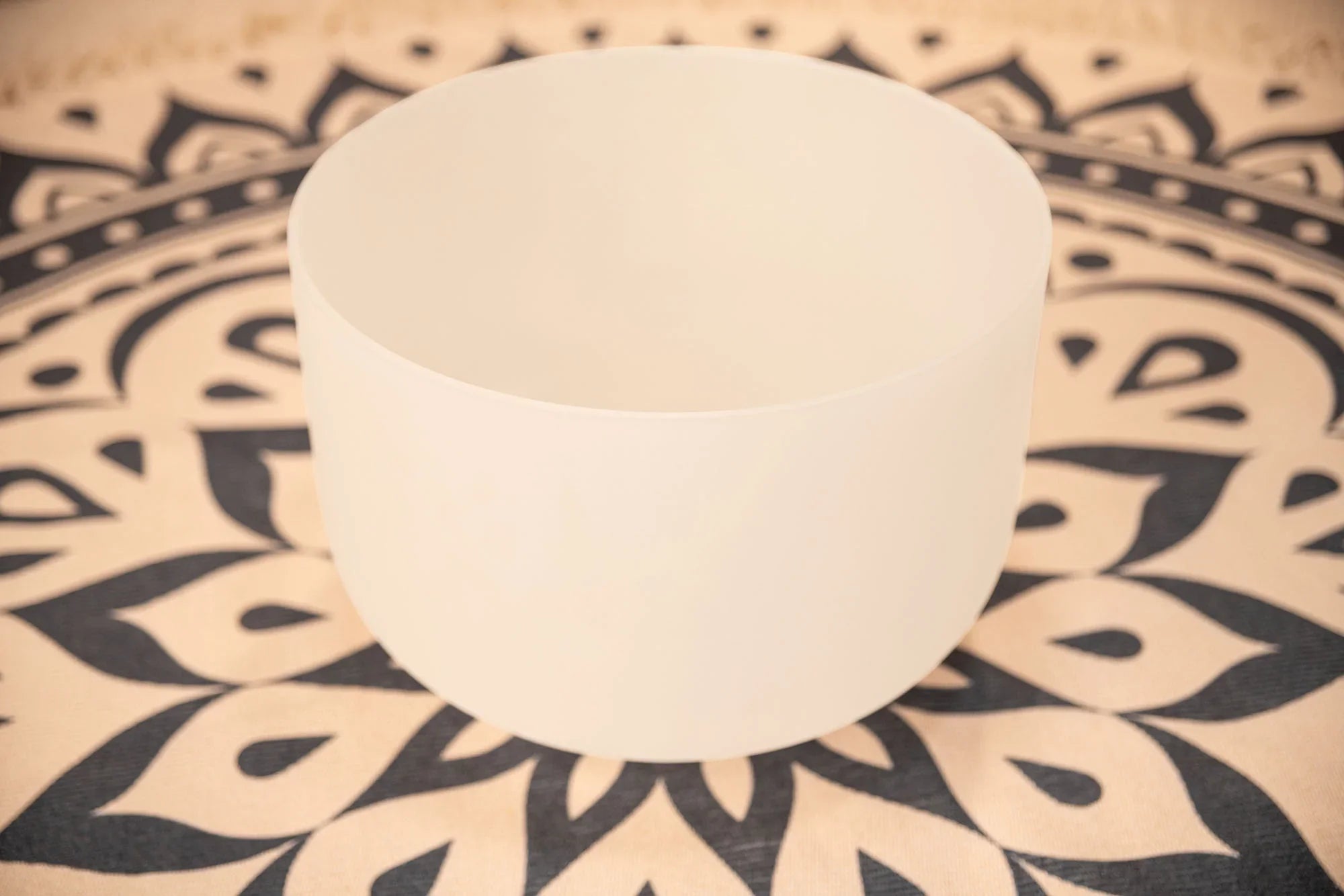 White crystal singing bowl on patterned mat for sound healing and meditation