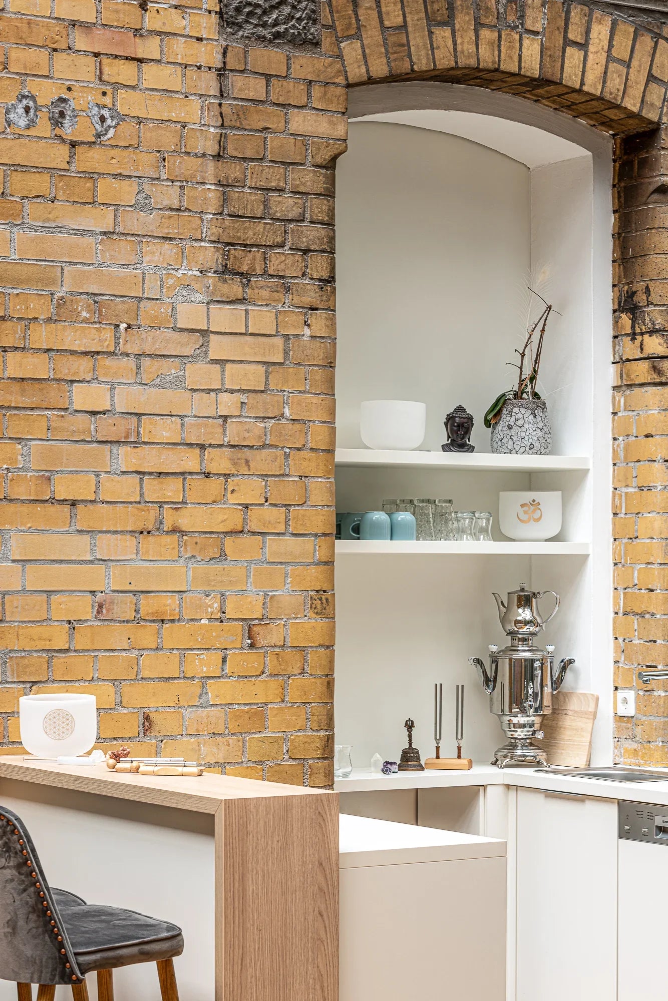 Sound healing instruments and singing bowls on modern kitchen shelves with brick wall background