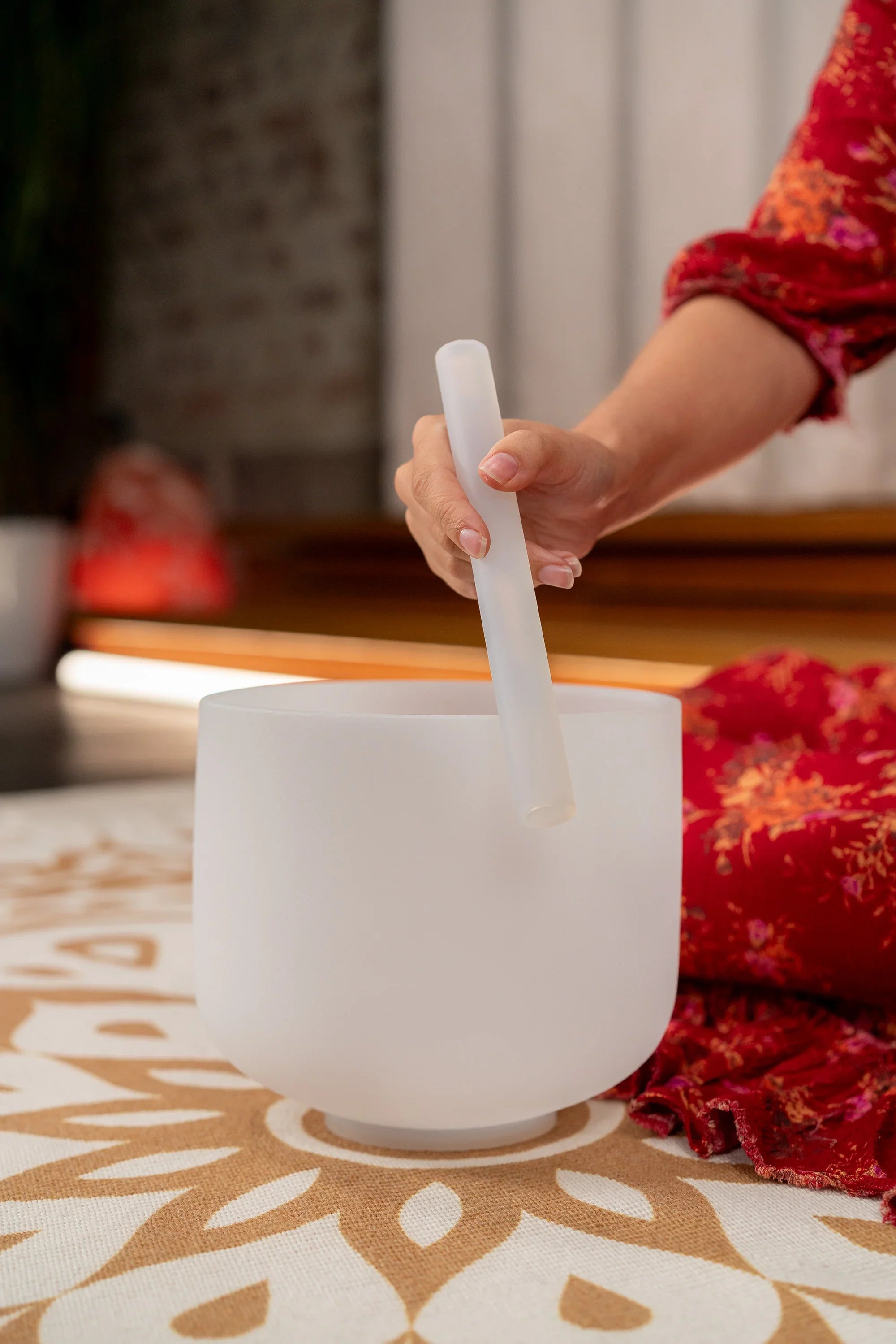 Hand playing a frosted crystal singing bowl with a mallet, used for sound healing
