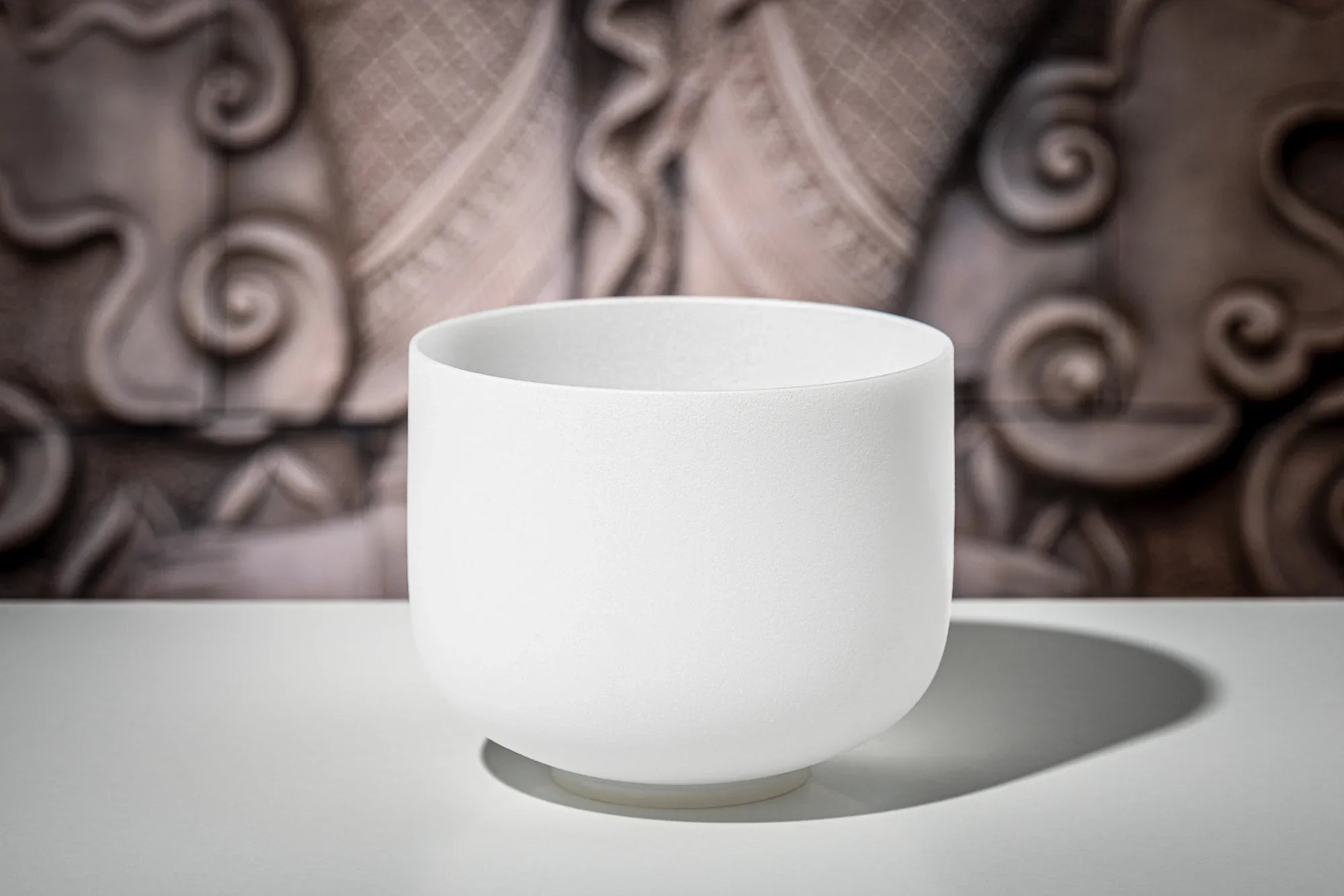 white crystal singing bowl on table with artistic background, sound healing instrument