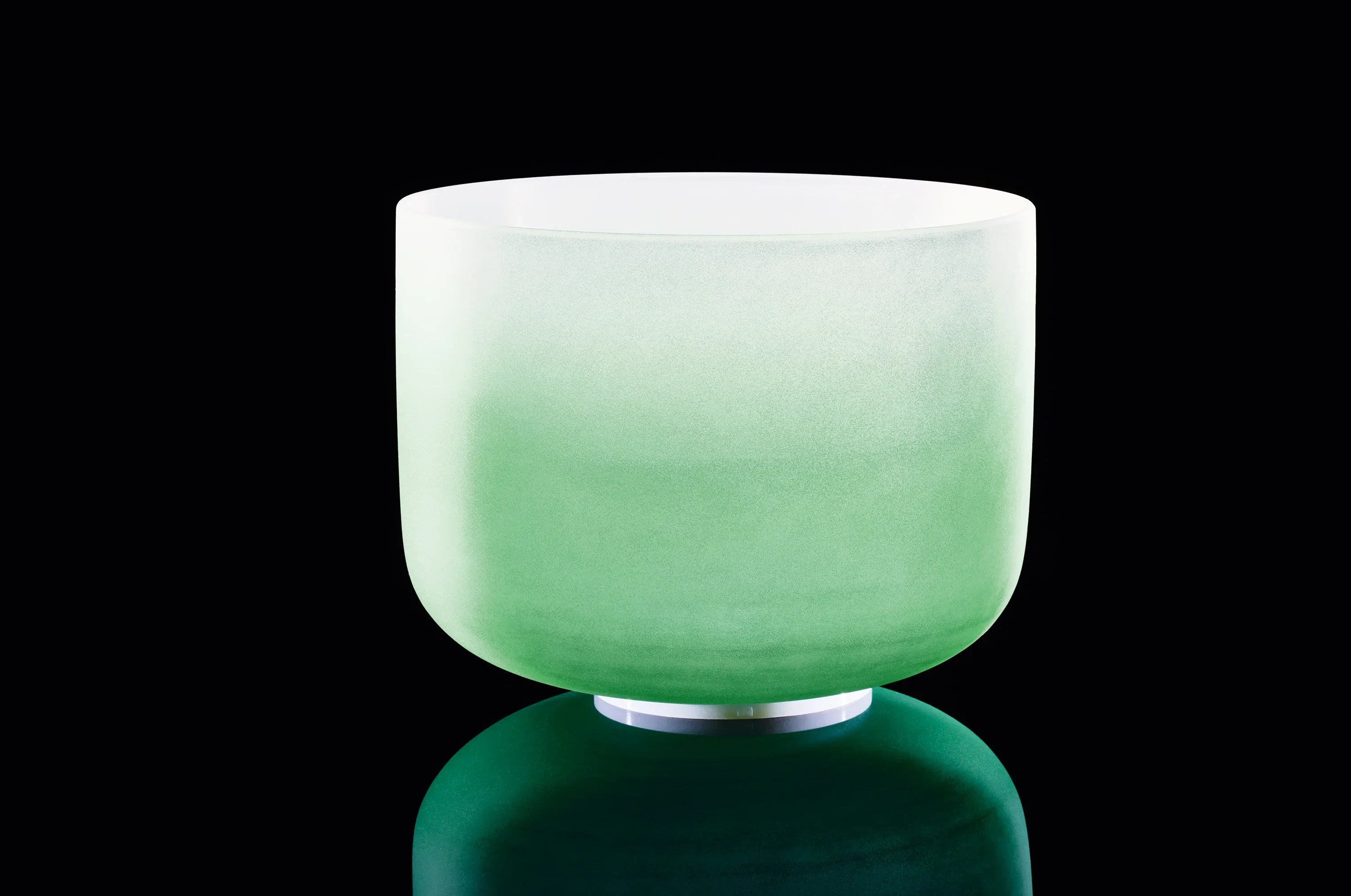 Green frosted crystal singing bowl for sound healing on dark background