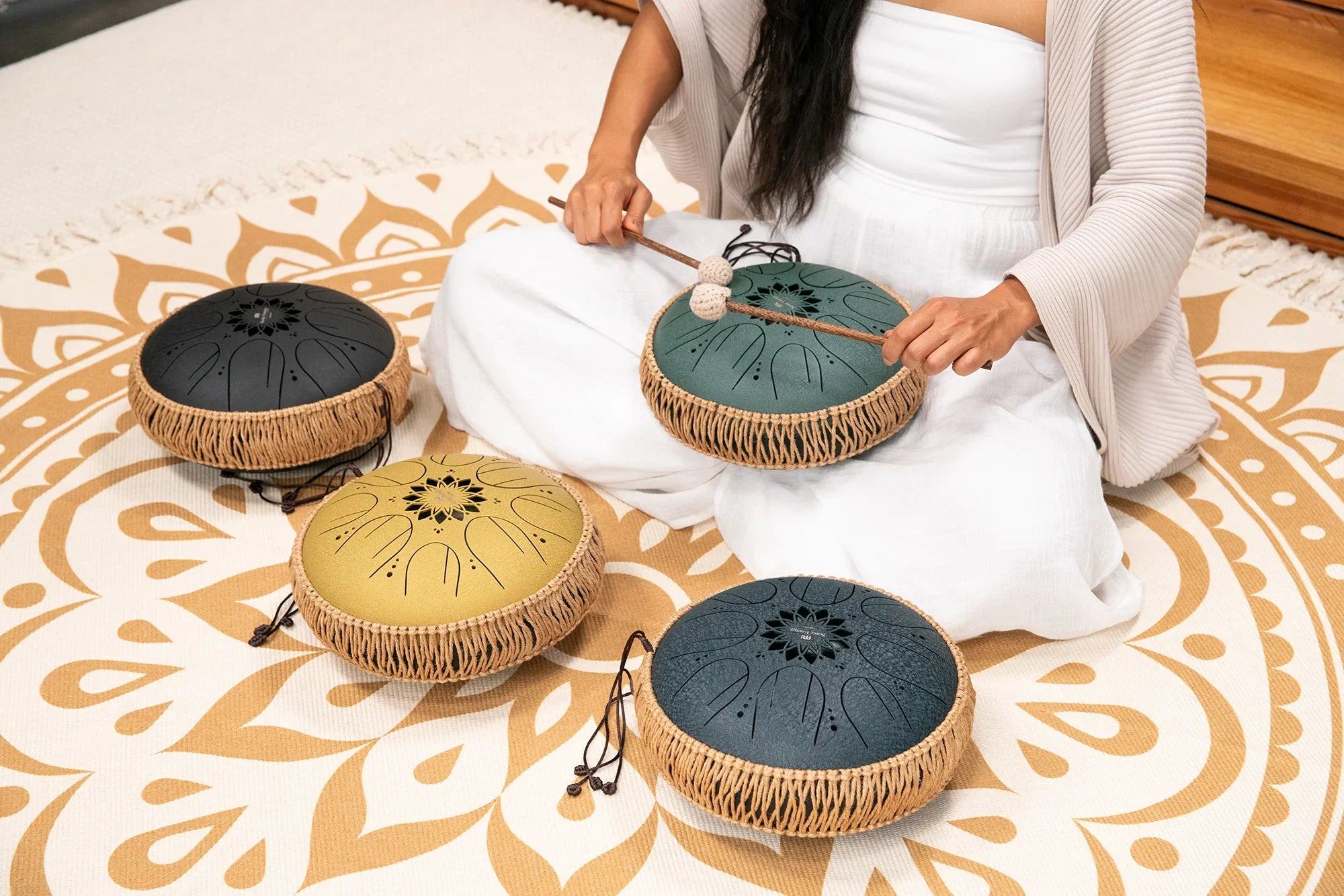 Person playing handpan drums for sound healing on a decorative mat