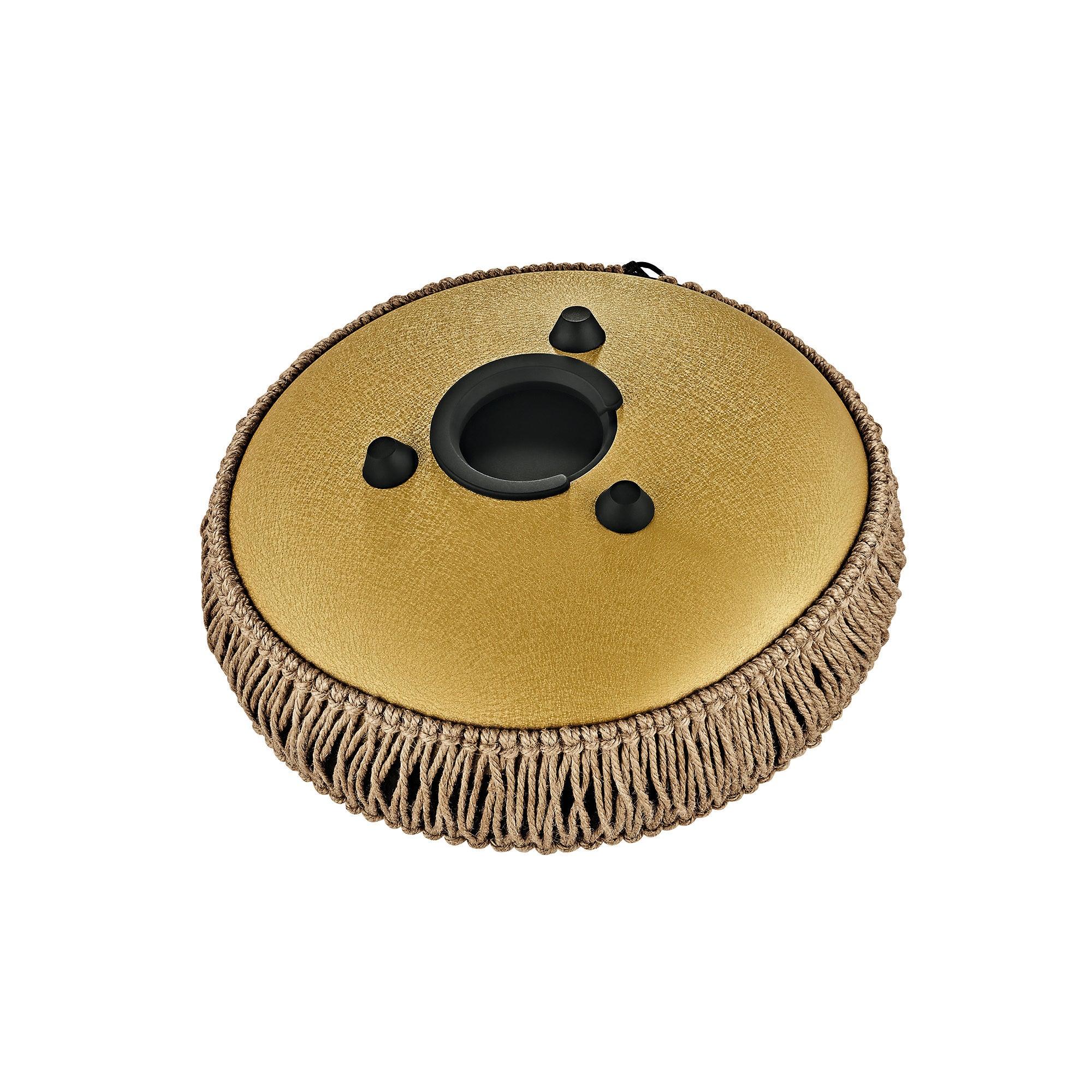 Gold metal tongue drum for sound healing with beige woven trim, on white background