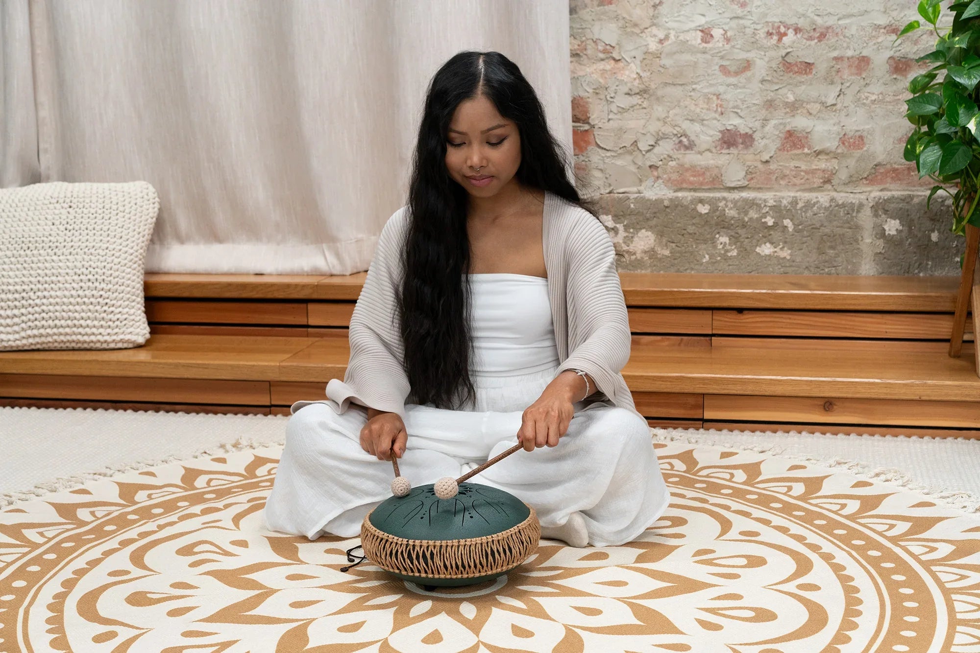 Woman playing hand drum tongue drum for sound healing in calm indoor setting