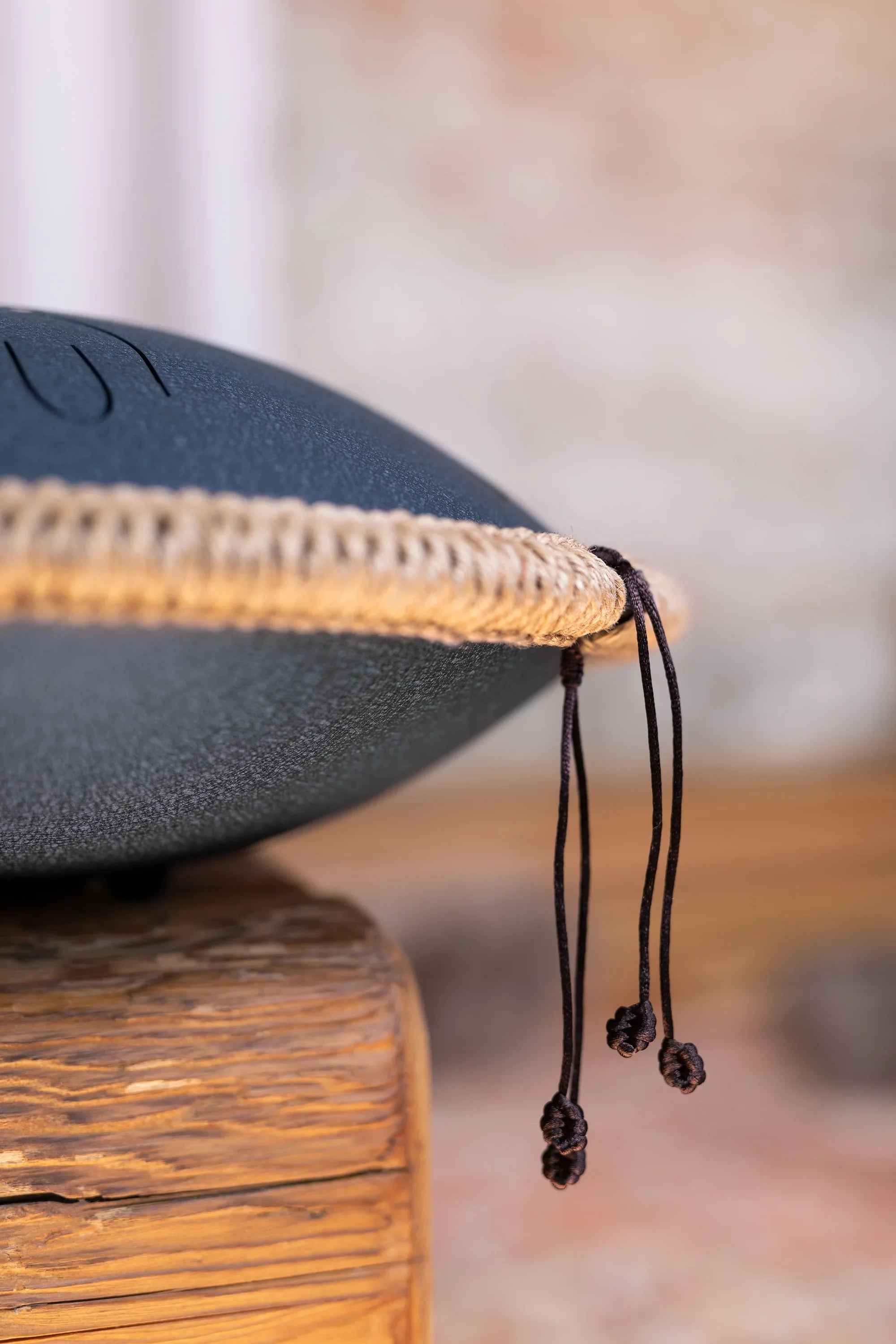 Close-up of a handpan sound healing instrument with rope edge detail on wooden surface