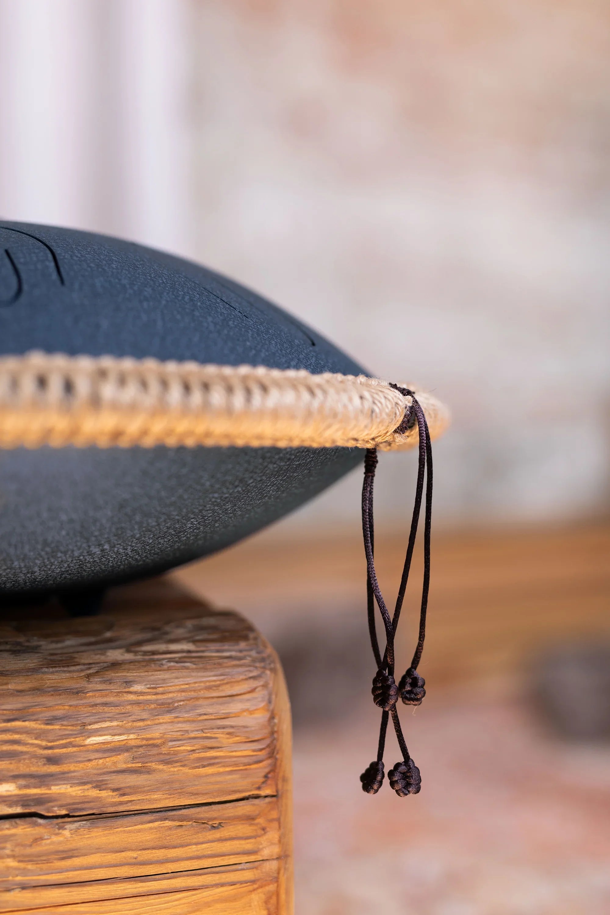 Close-up of a steel tongue drum with rope trim on a rustic wooden surface