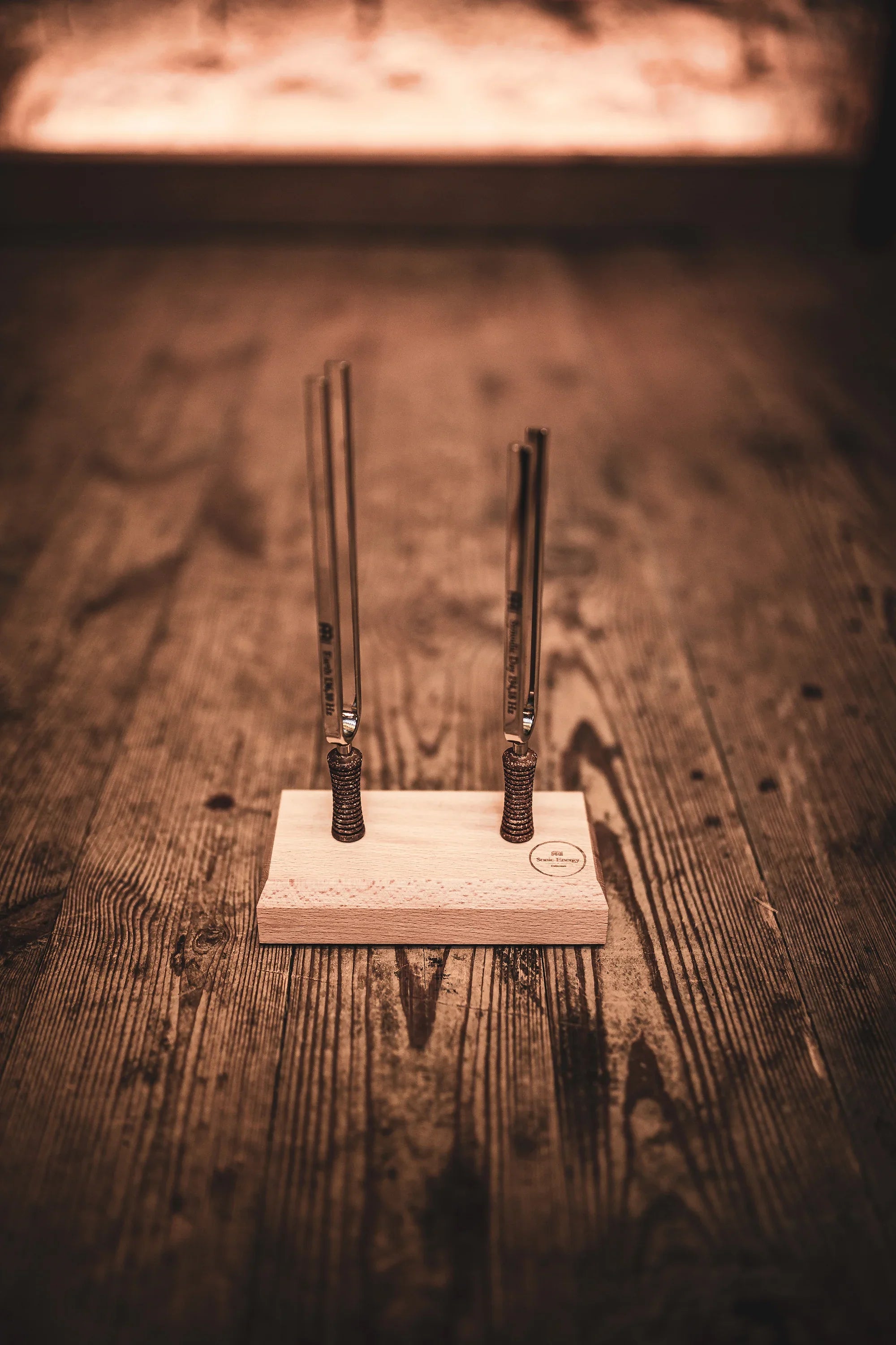 Four tuning forks on a wooden stand for sound healing on a rustic wooden floor