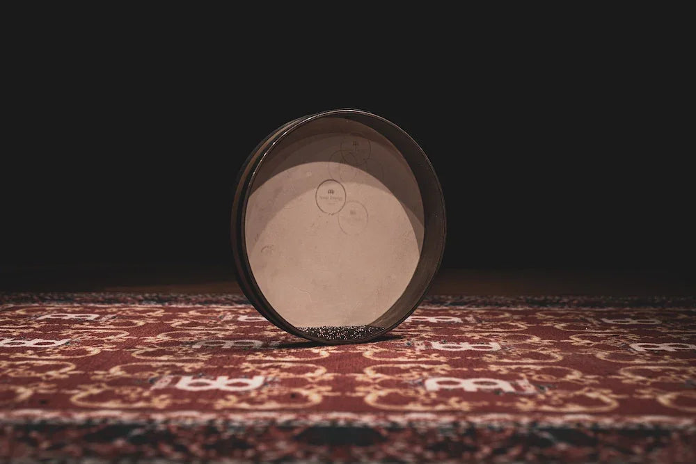 Frame drum for sound healing on patterned rug, musical instrument photography