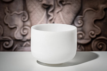 White crystal singing bowl on a table with decorative background, used for sound healing
