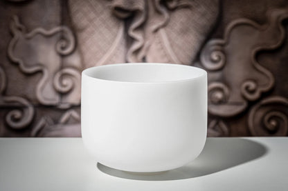 White crystal singing bowl for sound healing on a table with ornate background