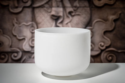 White crystal singing bowl for sound healing on a table with a textured background