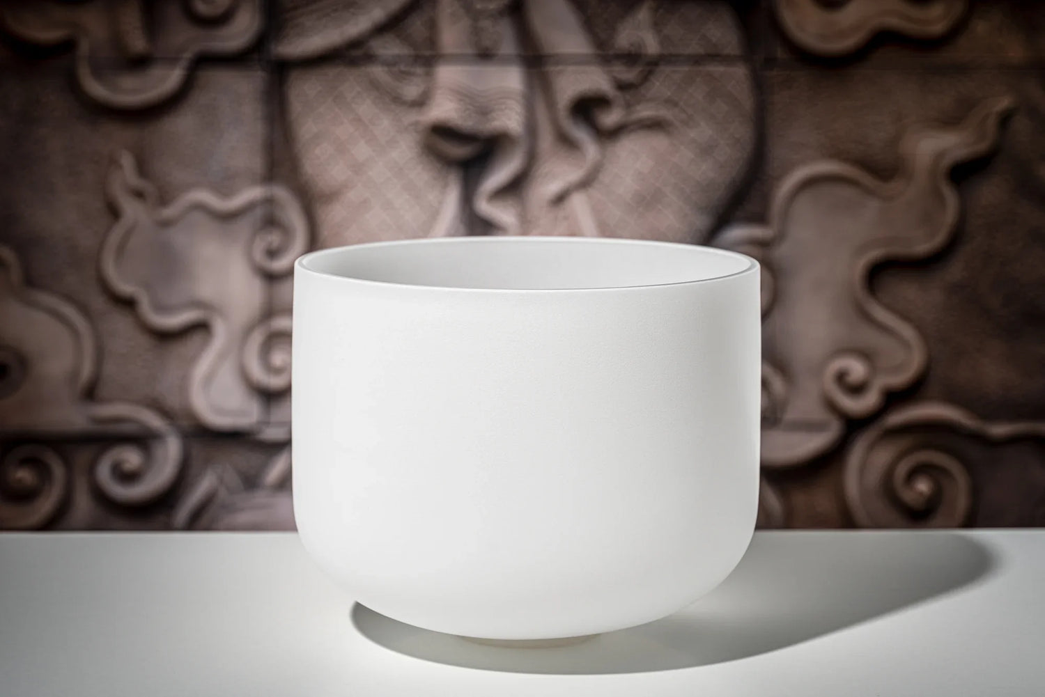White crystal singing bowl for sound healing on a table with artistic background