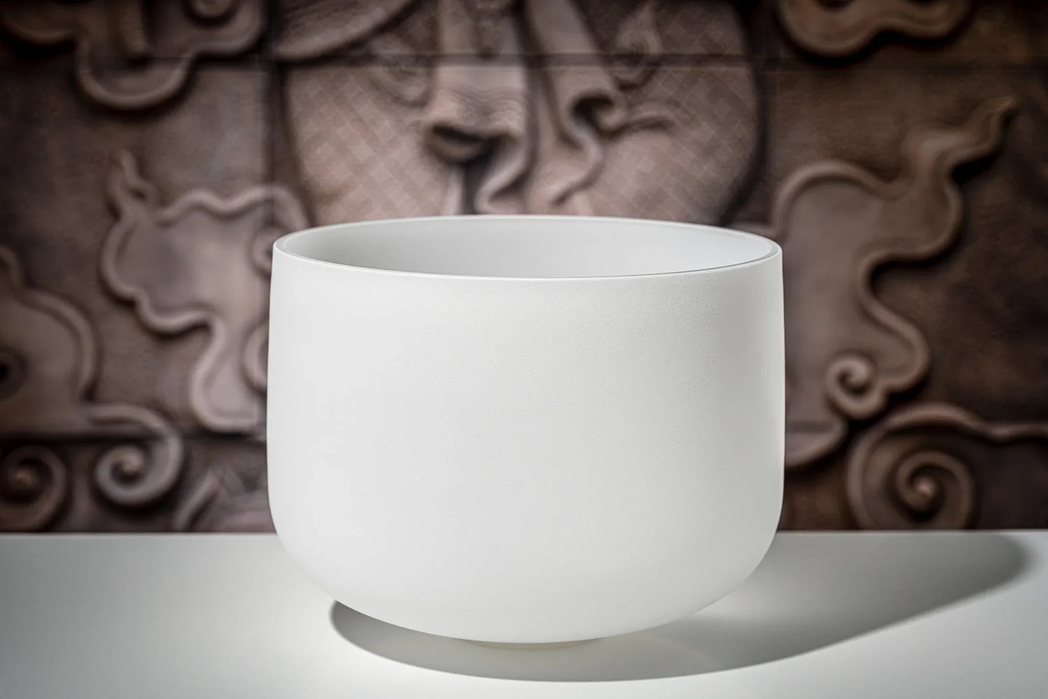 White crystal singing bowl for sound healing on a table with artistic background