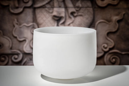 White crystal singing bowl for sound healing on a table with artistic background