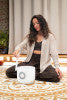 Woman using a white crystal singing bowl on a patterned rug in a peaceful indoor setting