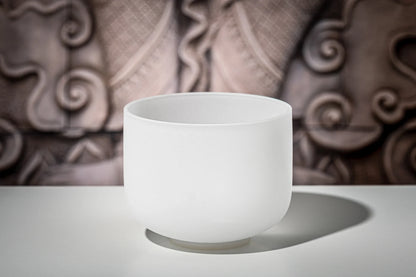 White crystal singing bowl on a table with artistic background, sound healing instrument