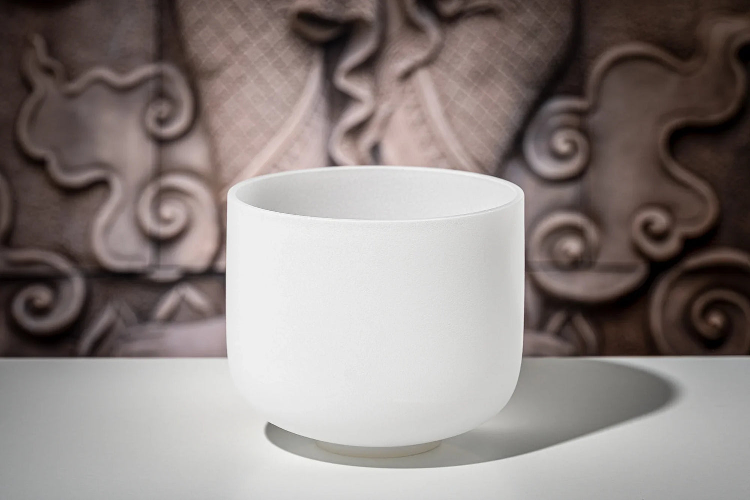 White crystal singing bowl for sound healing on table with artistic background