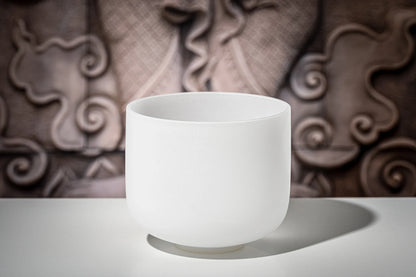 White crystal singing bowl for sound healing on table with artistic background