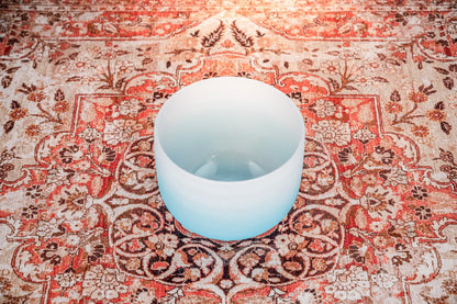 Frosted crystal singing bowl on a patterned floral rug for sound healing