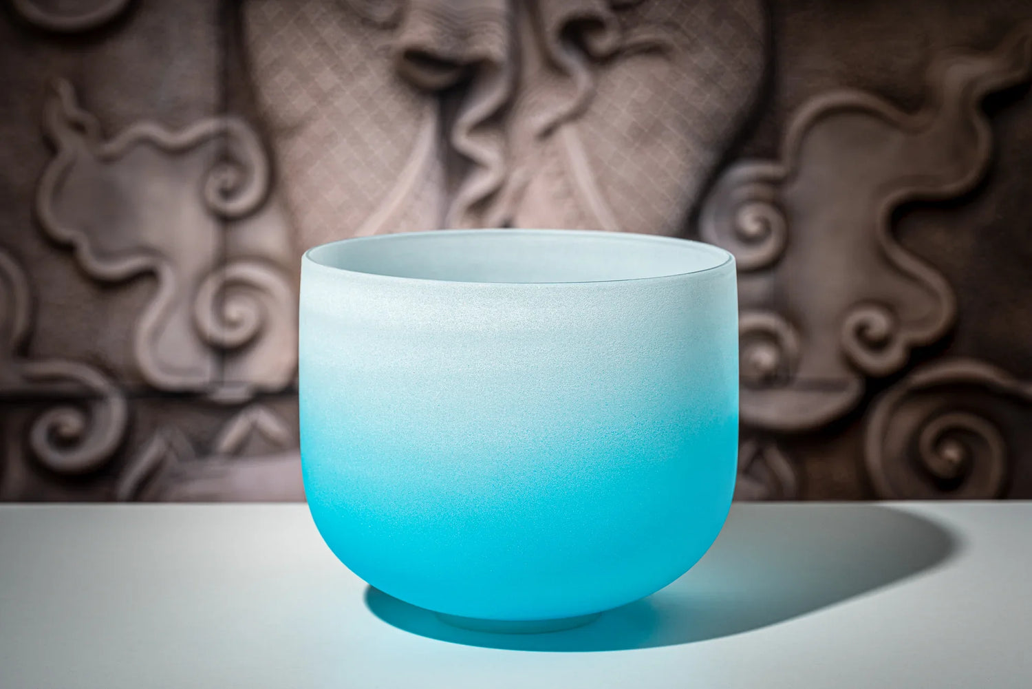 Blue crystal singing bowl for sound healing on a table with decorative background