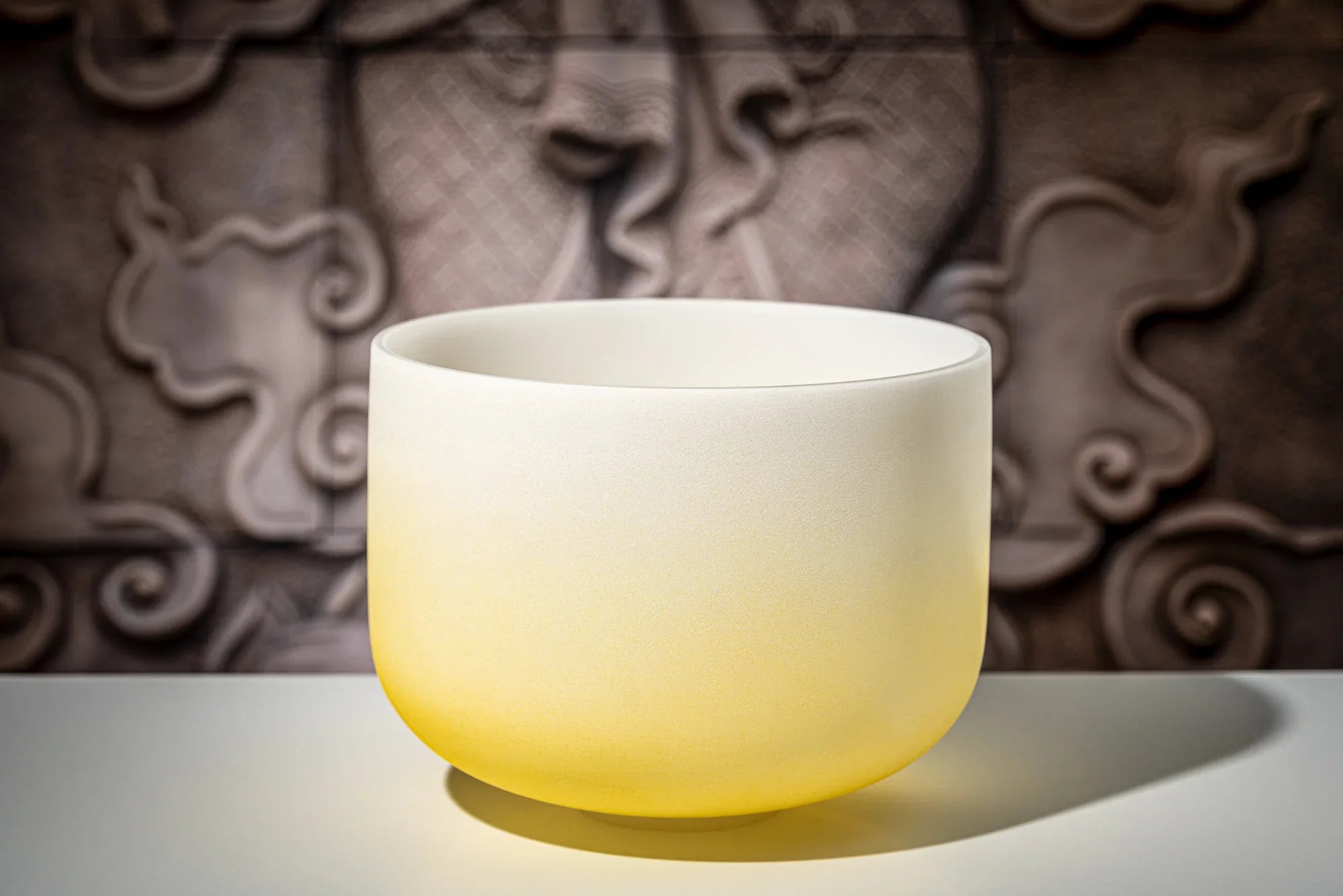 Yellow and white crystal singing bowl for sound healing on decorative background