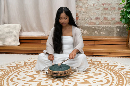 Woman playing hand drum tongue drum for sound healing in calm indoor setting