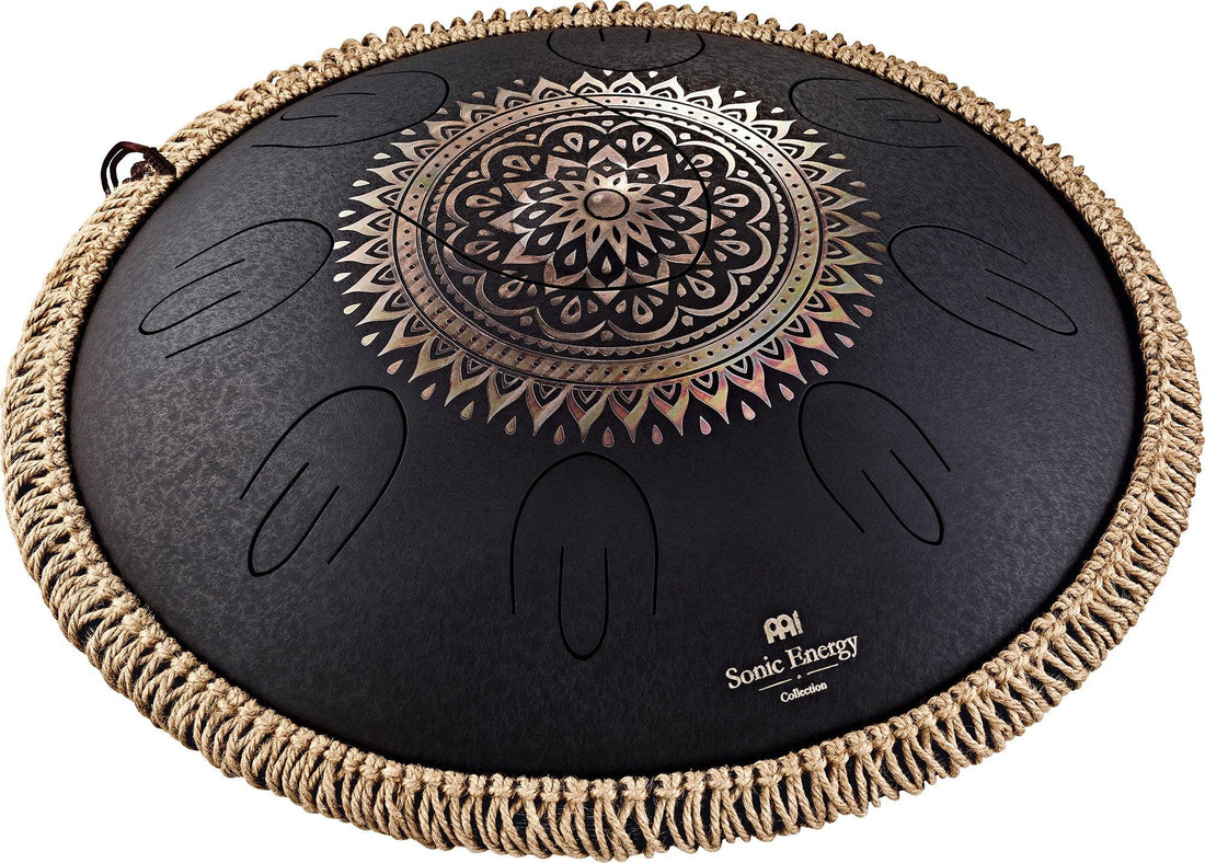 Black steel tongue drum with engraved mandala design and woven rope edge, used for sound healing