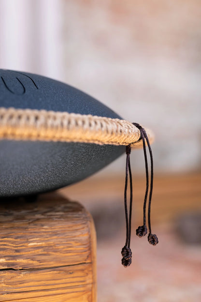 Close-up of a handpan sound healing instrument with rope edge detail on wooden surface
