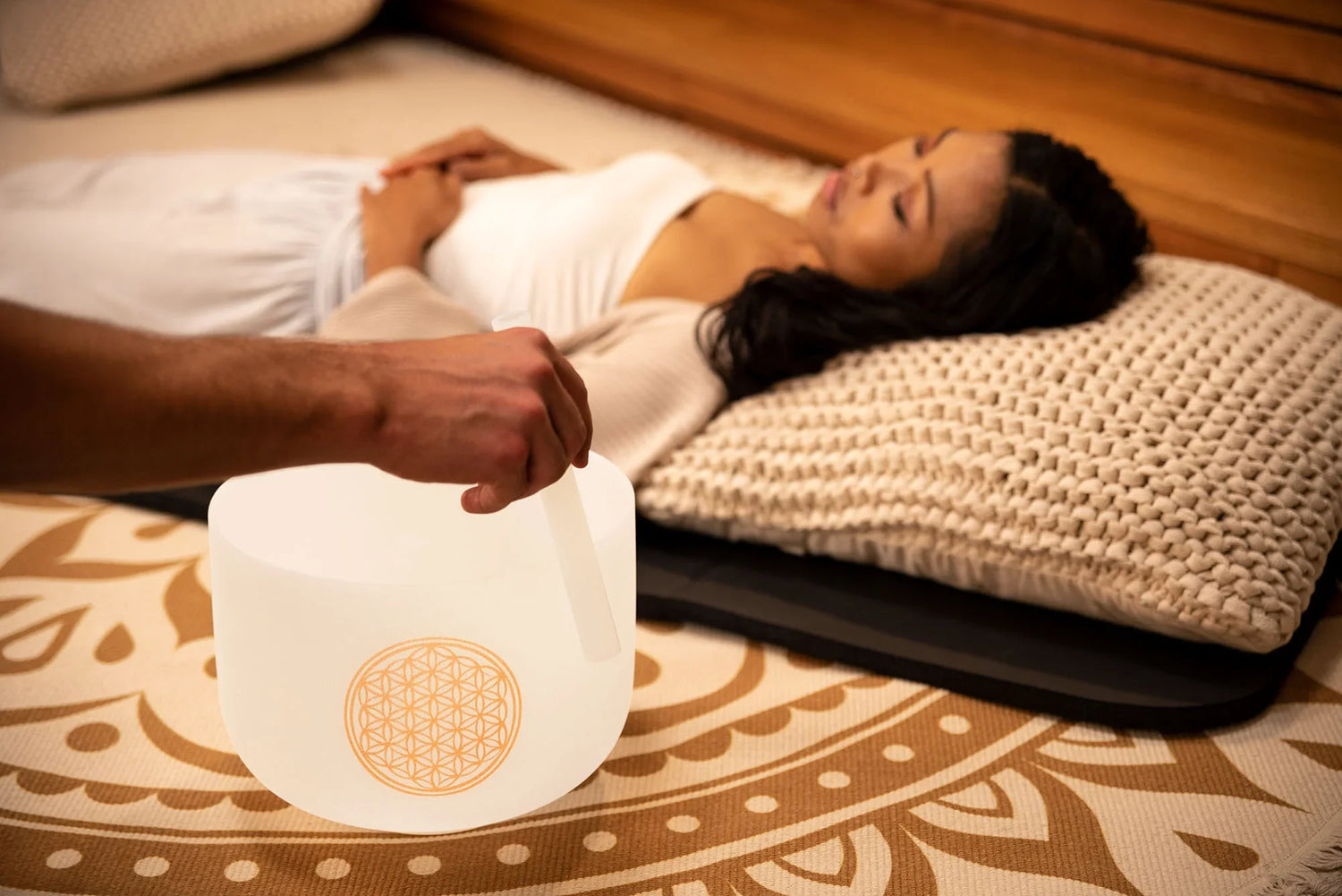 Sound healing session with crystal singing bowl and relaxed woman on cushion