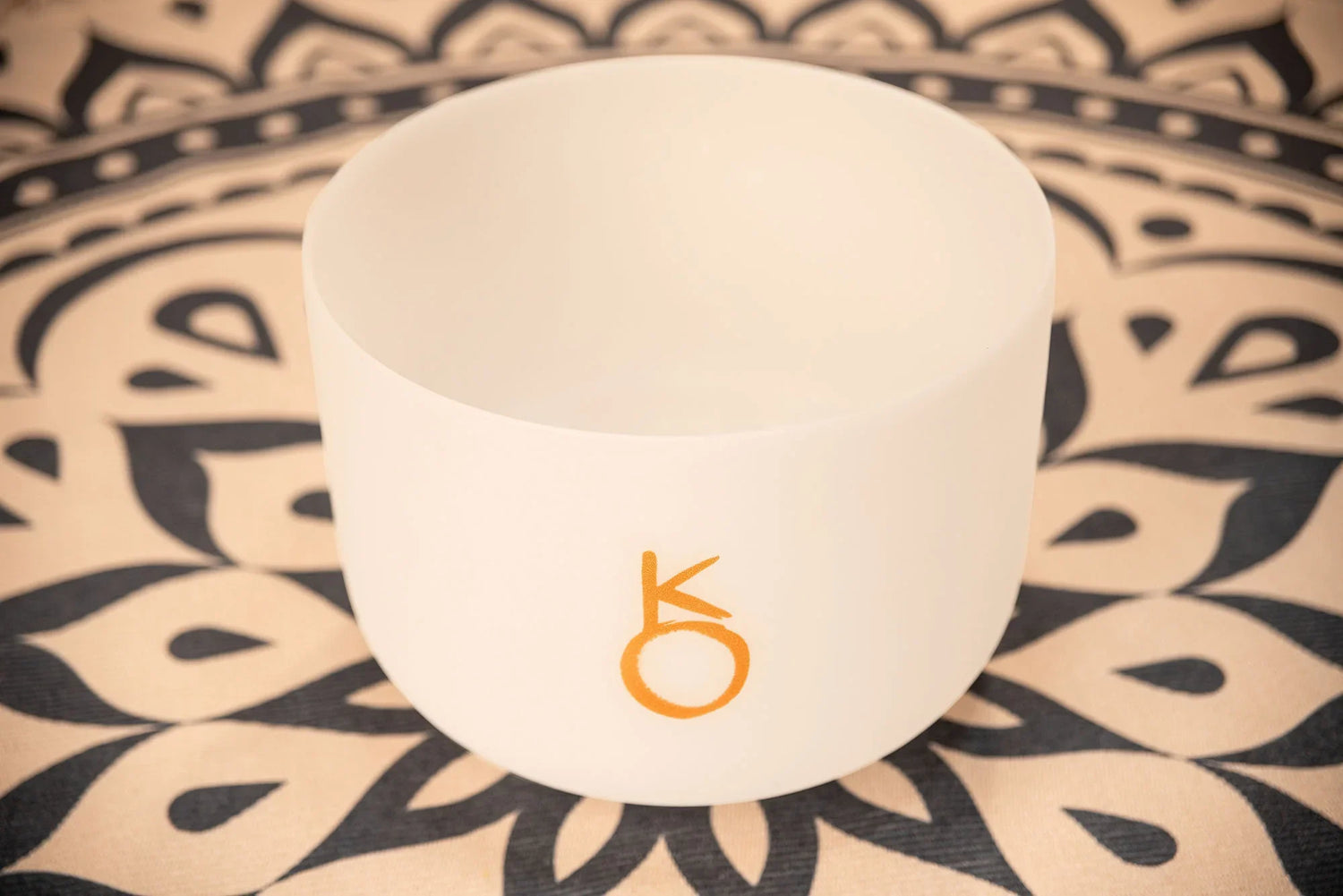 White crystal singing bowl for sound healing on decorative patterned mat