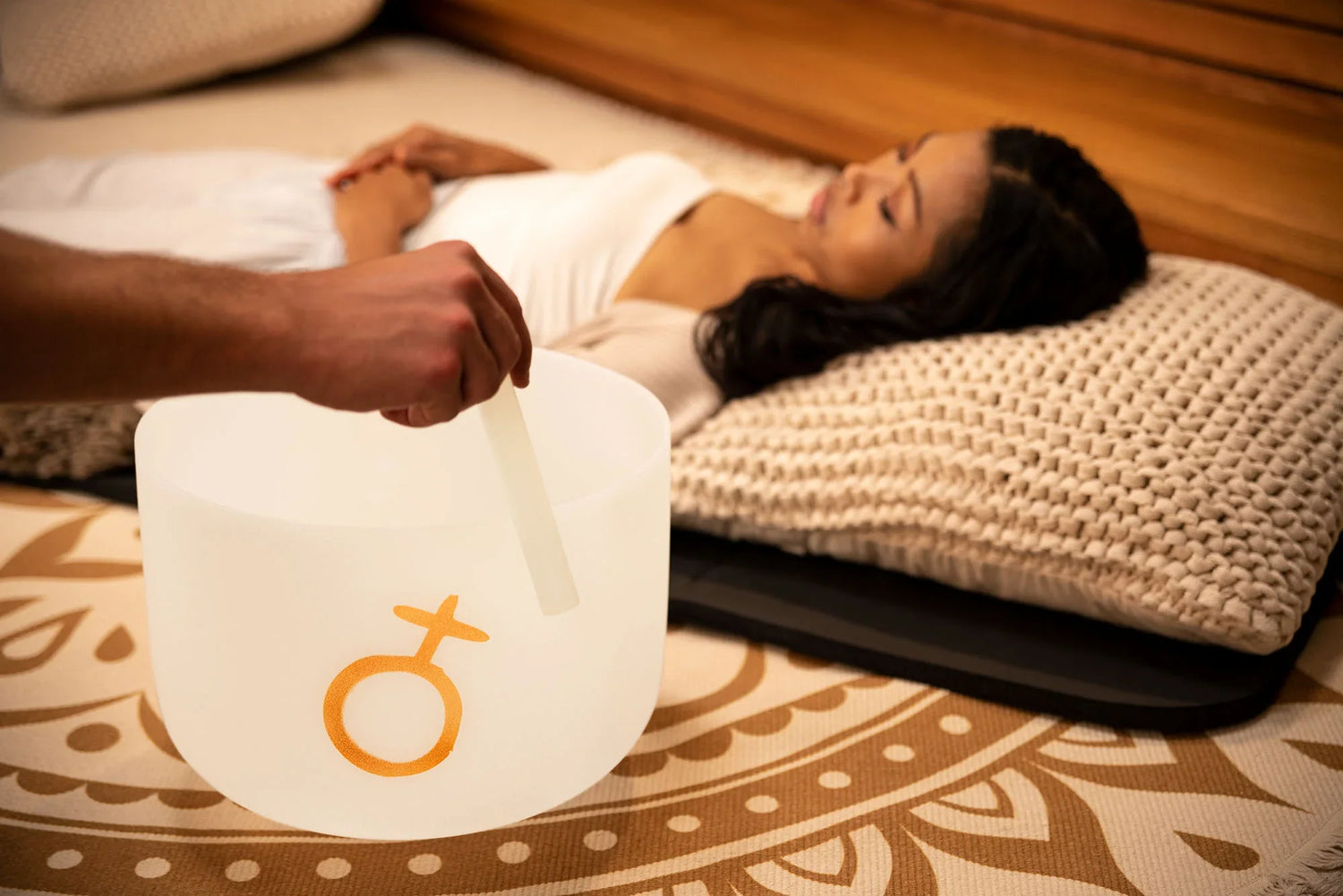 Sound healing session with crystal singing bowl near relaxed woman lying on mat