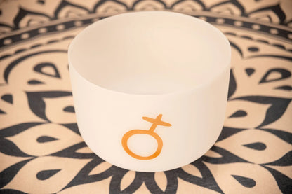 Frosted crystal singing bowl with orange Venus symbol on mandala mat, sound healing instrument