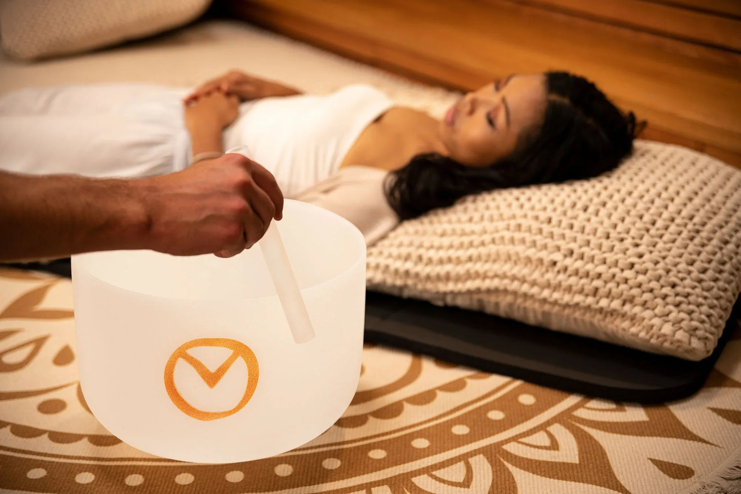 Sound healing session with crystal singing bowl and person lying relaxed on mat