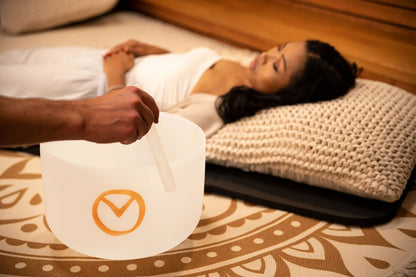 Sound healing session with crystal singing bowl and person lying relaxed on mat