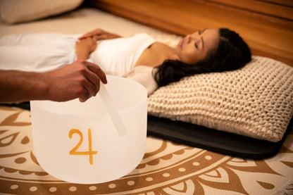 Woman relaxing on pillow during sound healing with crystal singing bowl