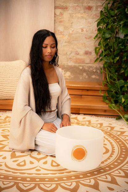 Woman meditating indoors with a frosted crystal singing bowl for sound healing