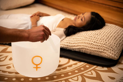 Sound healing session with a frosted crystal singing bowl near a relaxed woman lying on a mat