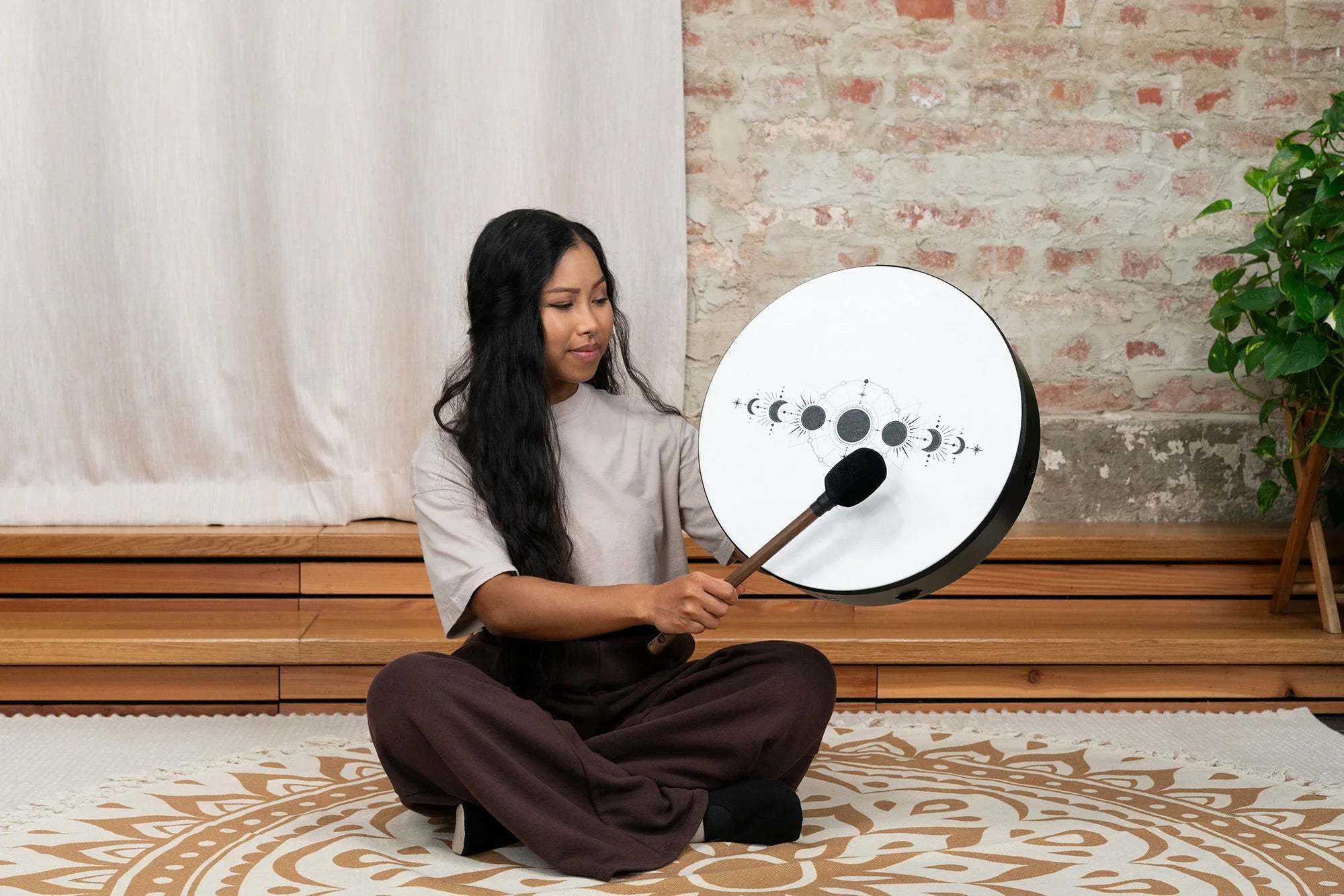 Woman playing a moon phase shamanic drum for sound healing indoors