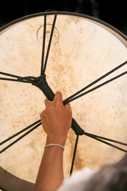 Hand gripping corded handle of large frame drum for sound healing session