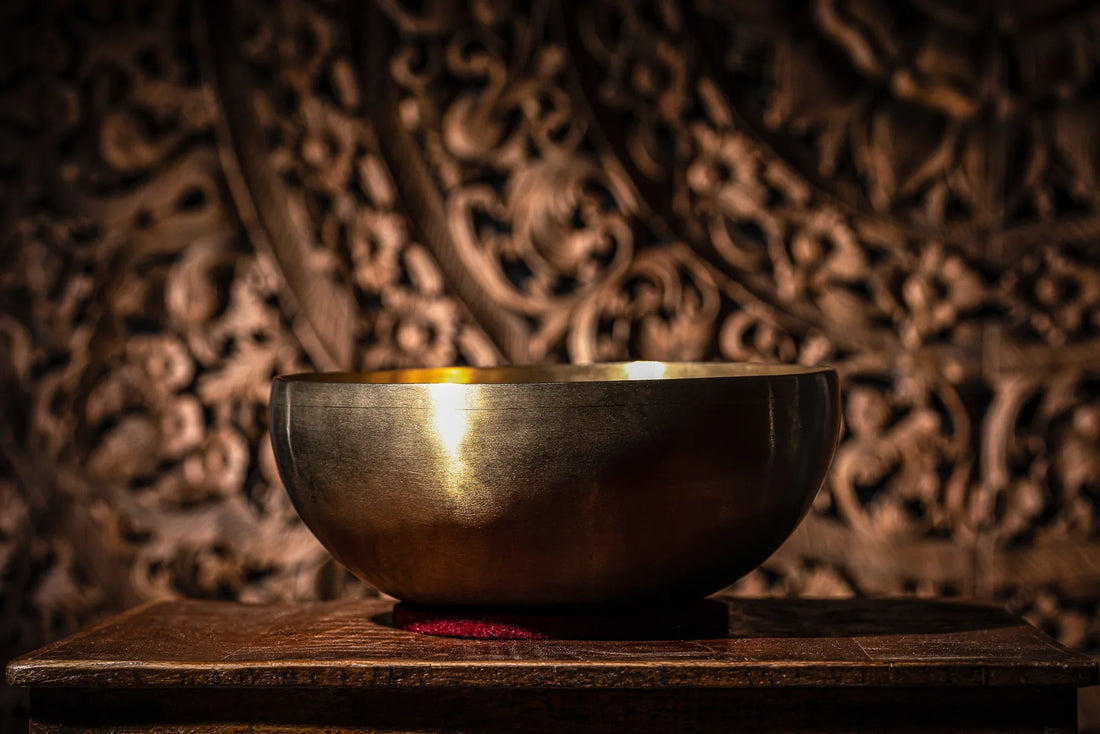 Brass singing bowl for sound healing on wooden table with ornate background