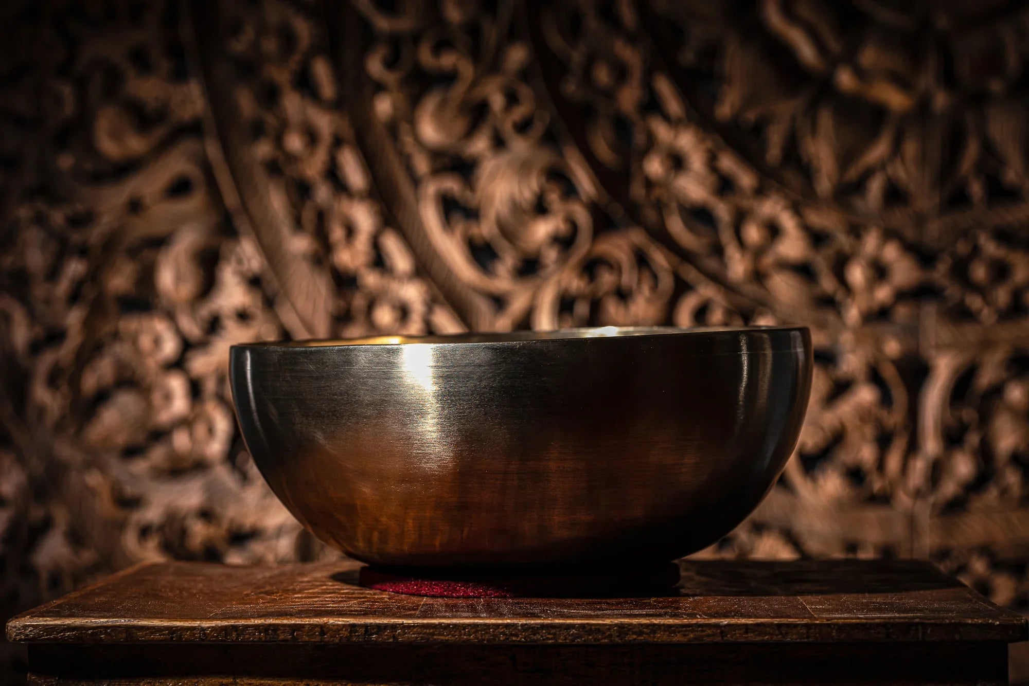 Metal singing bowl for sound healing on wooden table with ornate background