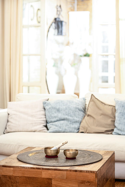 Tibetan singing bowls with mallet on table in cozy living room setting