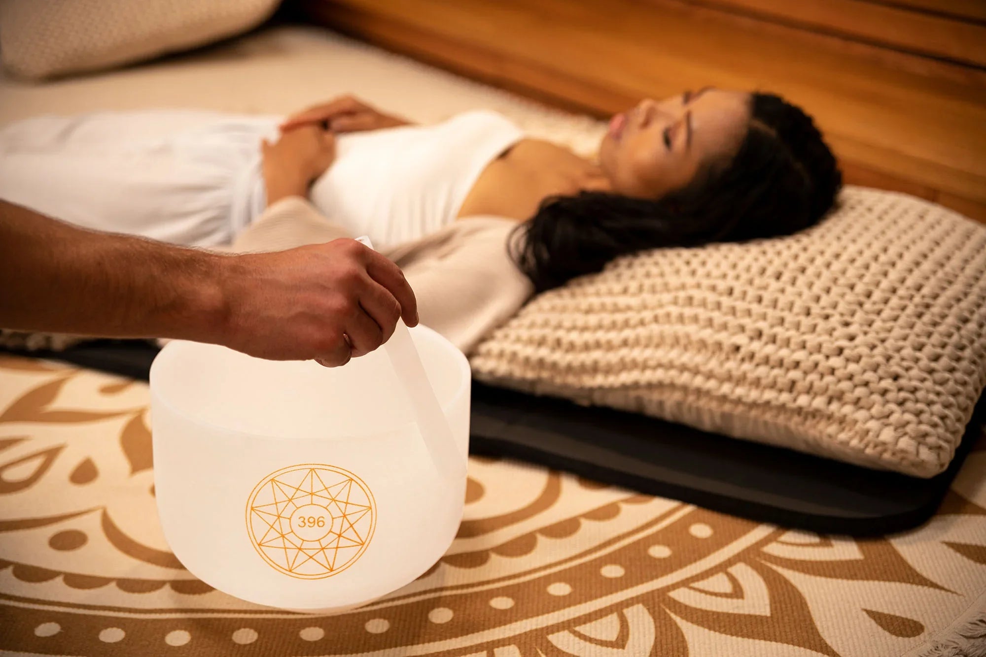 Crystal singing bowl sound healing session with woman relaxing on mat
