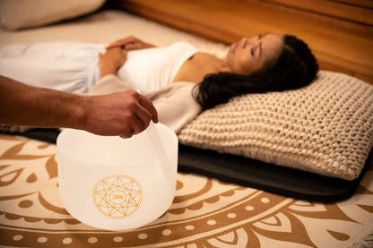 Crystal singing bowl sound healing session with woman relaxing on mat