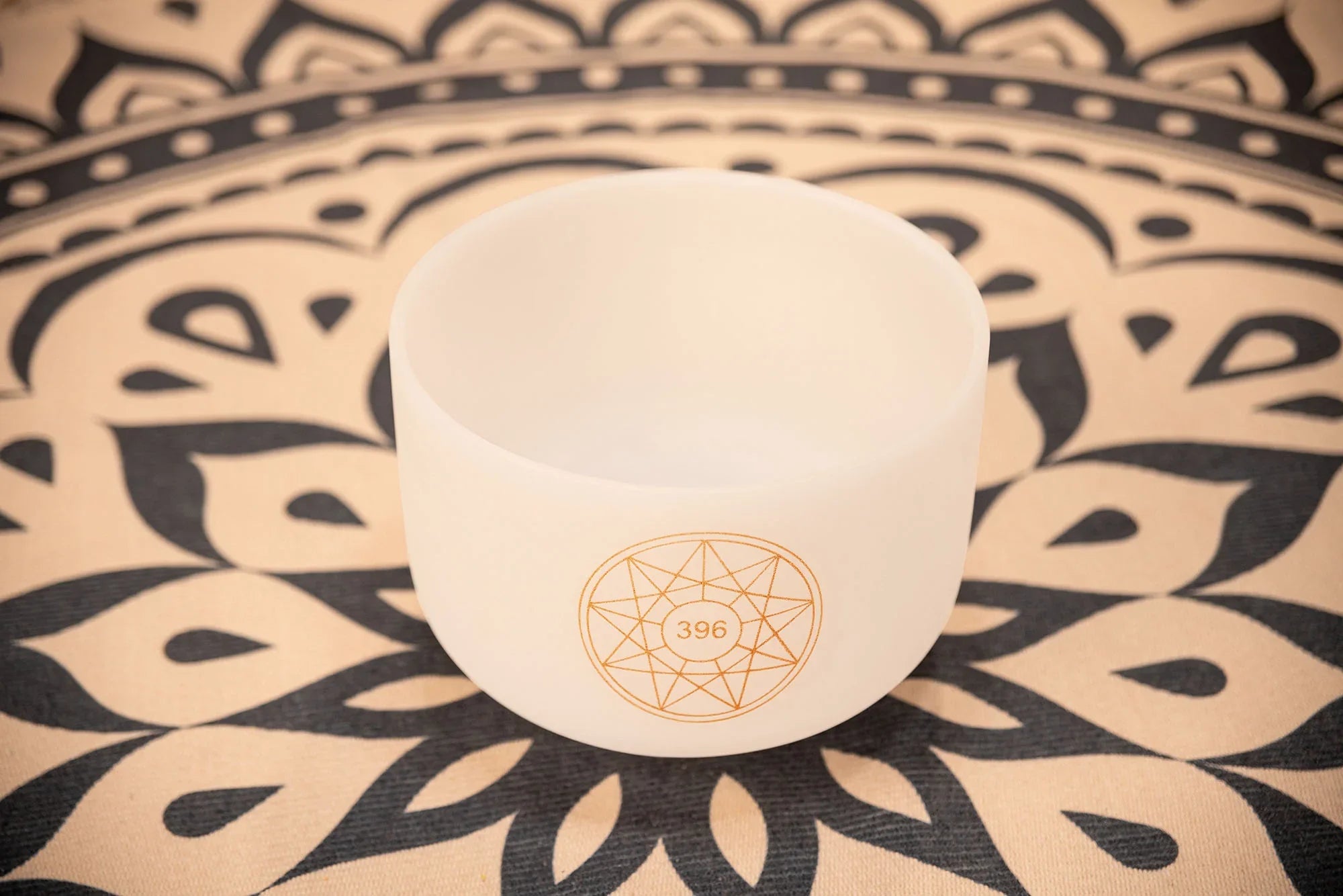 Crystal singing bowl with 396 Hz symbol on patterned mat, used for sound healing and meditation