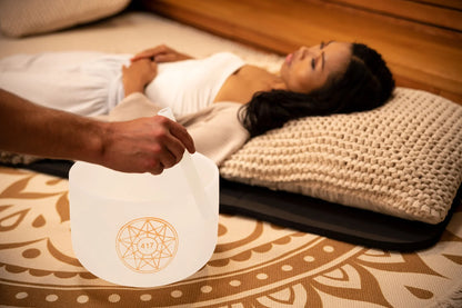 Sound healing session with crystal singing bowl and relaxed woman lying on mat